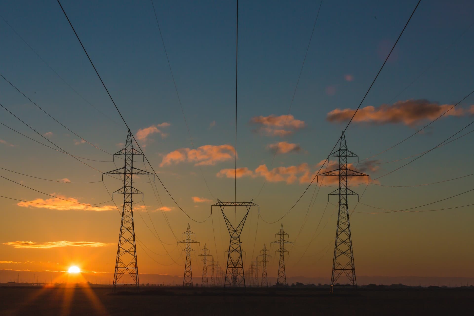 Hoogspanningsmasten in een open landschap bij zonsondergang